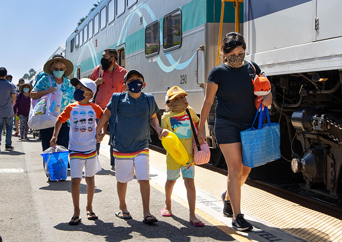 Masked families walking along a Metrolink train platform