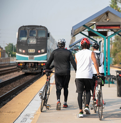 Cyclists walking along a train platform