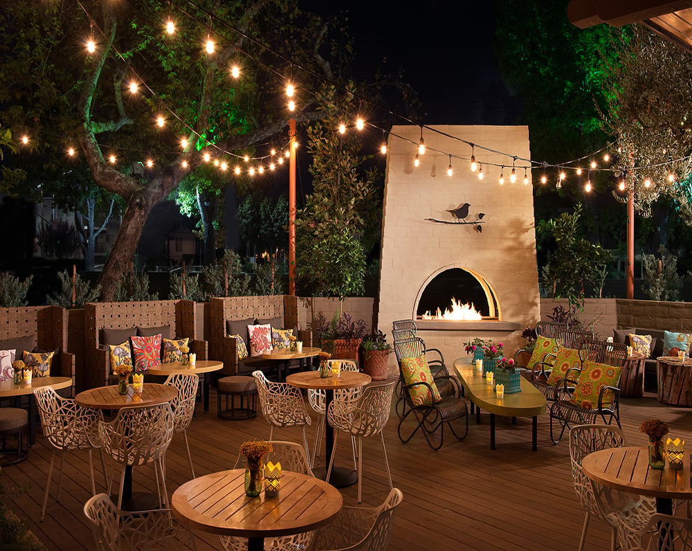 Outside patio with fireplace lit by string lights
