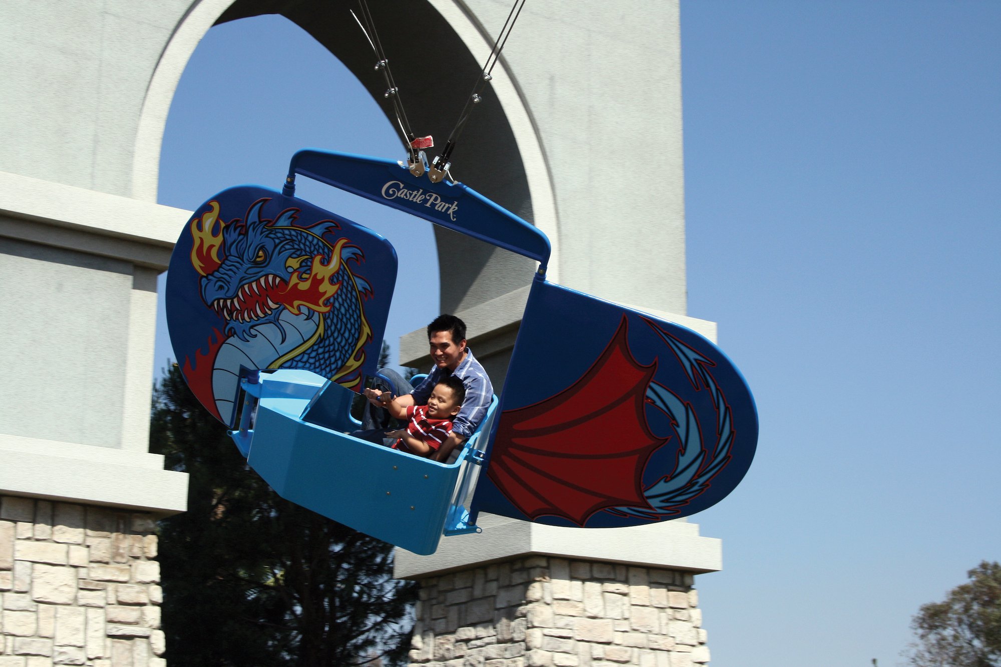 A man and young boy riding the Dragon Flyer at Castle Park.
