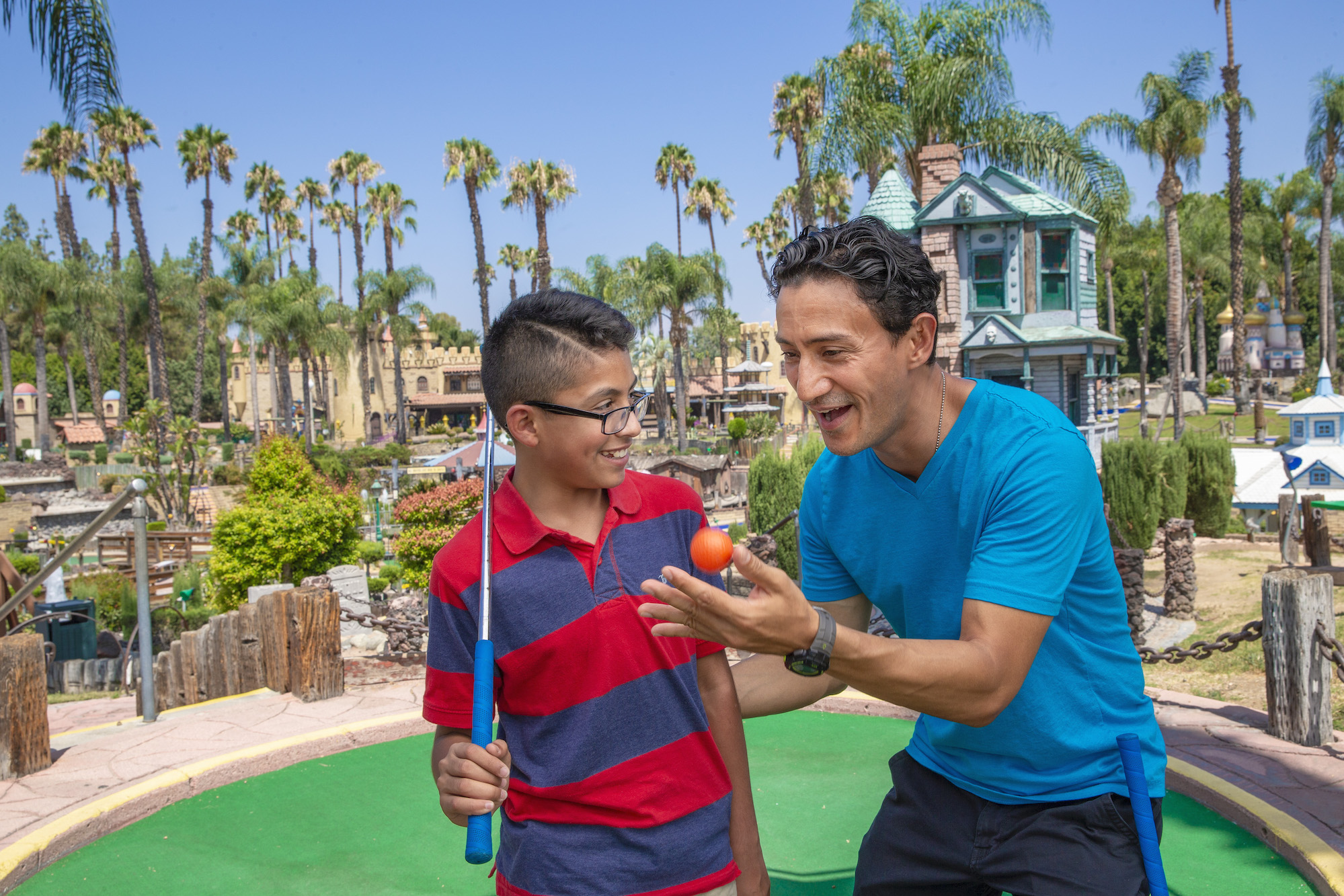 A man and his son playing miniature golf at Castle Park.