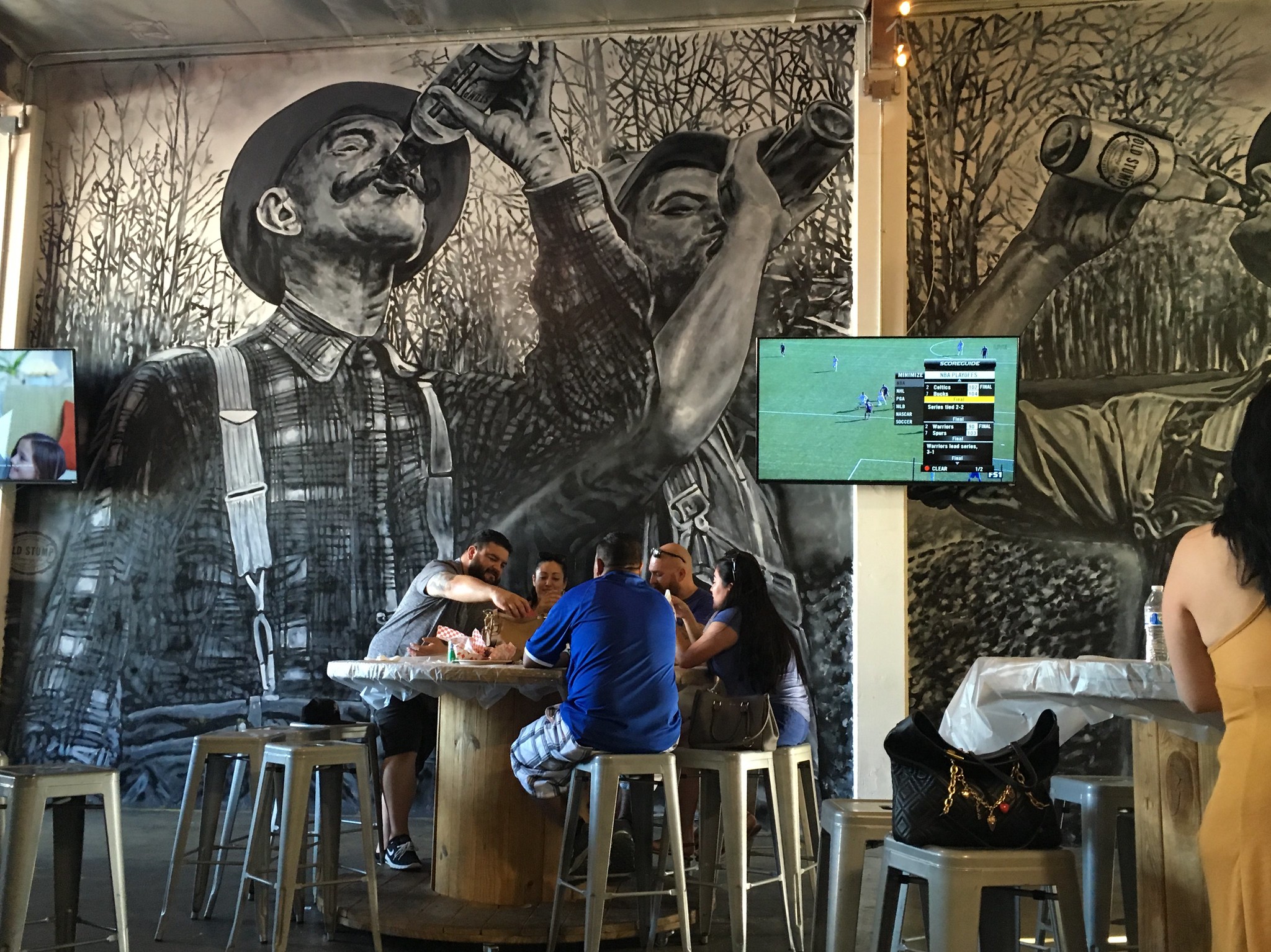 Customers drinking in front of a large mural